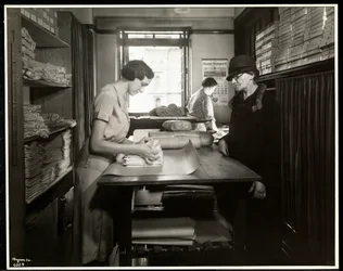 Ung kvinde pakker stofmaterialer ind, som en hjemmearbejder kan tage med, hos New York Association for the Blind, 111 East 59th Street, New York, 1931 (sølv gelatinetryk)